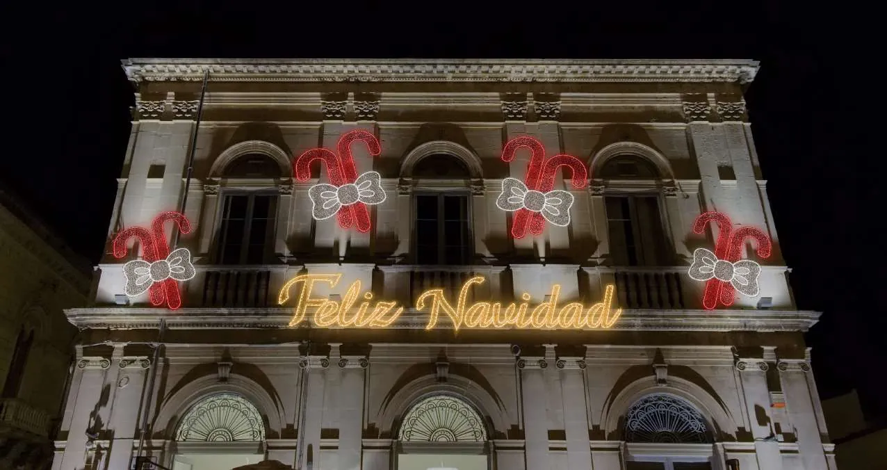 Fachada de cantera iluminada con bastones de dulce y letrero 'Feliz Navidad'