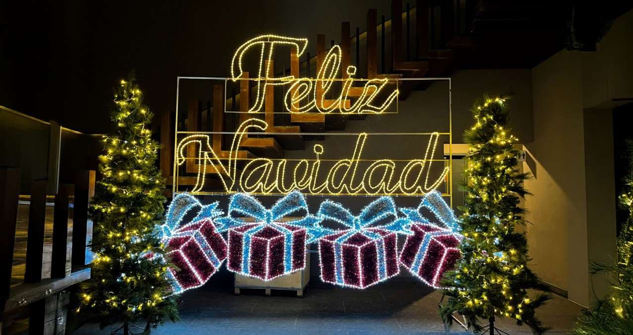 Montaje de letras 'Feliz Navidad' con regalos iluminados para evento